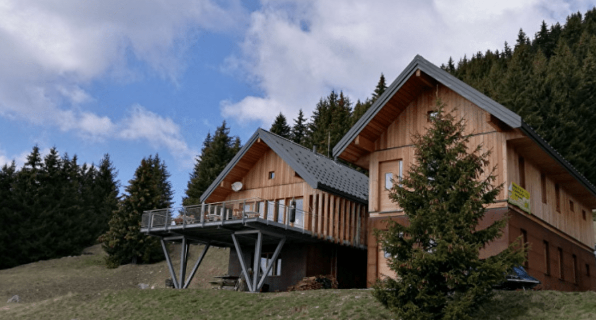 Refuge de montagne en bois composé de 2 bâtiments avec sapins en arrière-plan