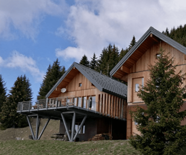 Refuge de montagne en bois composé de 2 bâtiments avec sapins en arrière-plan