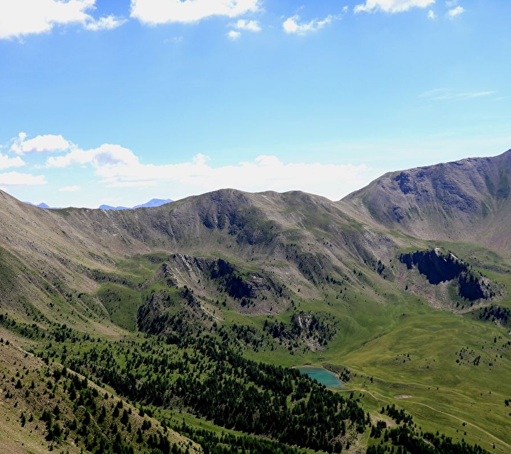 Vue plongeante sur un lac et sa forêt de sapins entourés de montagnes