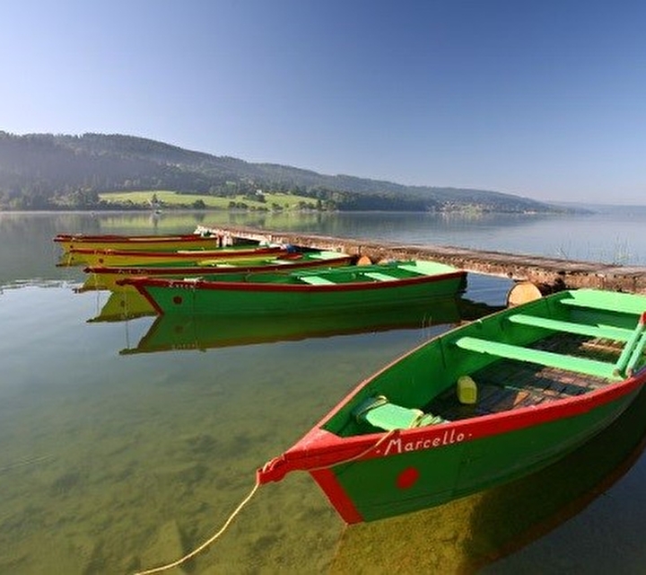 Barques colorées attachées à un ponton face aux montagnes