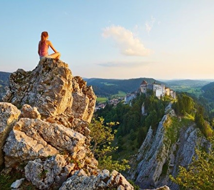 Jeune femme assise au sommet d'une montagne contemplant le vue sur les montagnes verdoyantes
