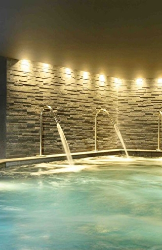 Vue sur la piscine intérieure d'un spa et sur son espace détente