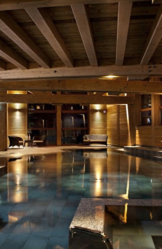 Vue sur la piscine éclairée d'un spa dans un chalet en bois