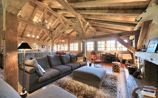Vue intérieure d'un chalet de montagne en bois avec un salon aménagé comprenant meubles et canapé