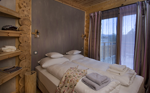Intérieur d'un chalet et d'une chambre avec lit double et étagères