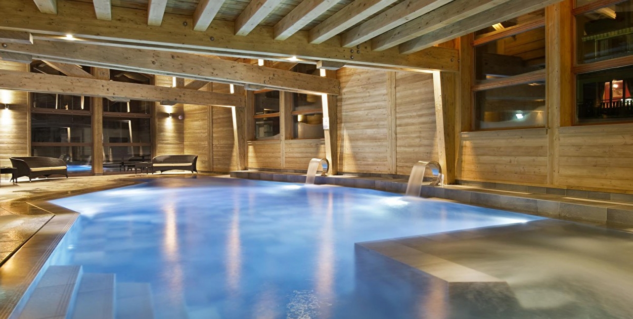 Vue sur la piscine intérieure d'un spa et sur son espace détente avec canapés et tables basses