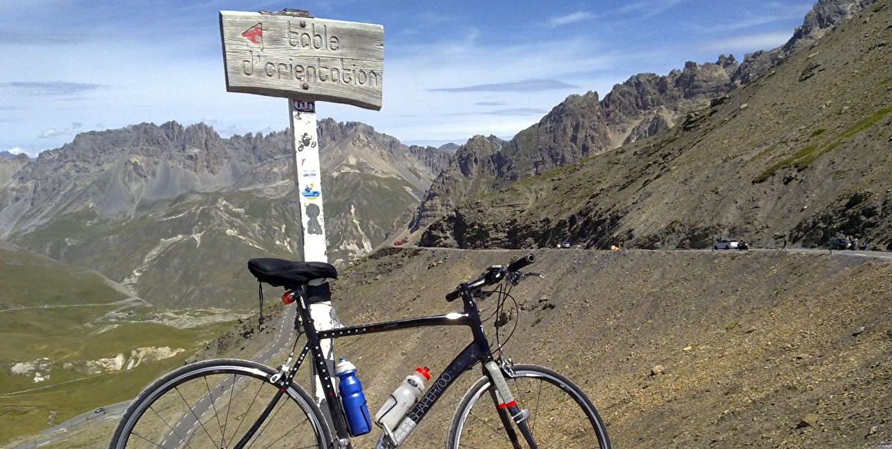 Vélo posé sur un panneau de signalisation indiquant la table d'orientation le long d'une route de montagne