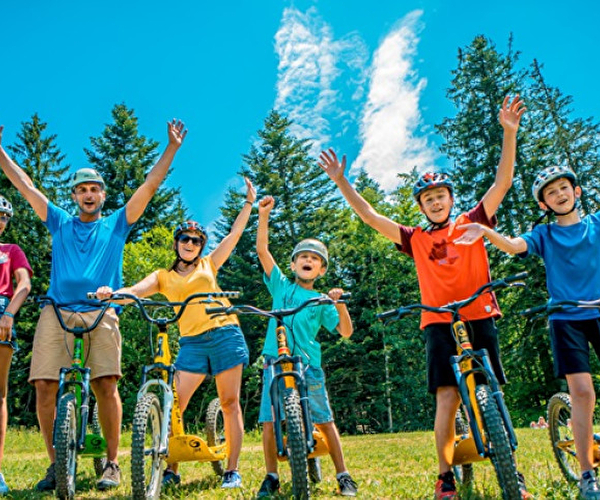 Famille en vélo levant les bras en l'air lors d'une ballade en montagne