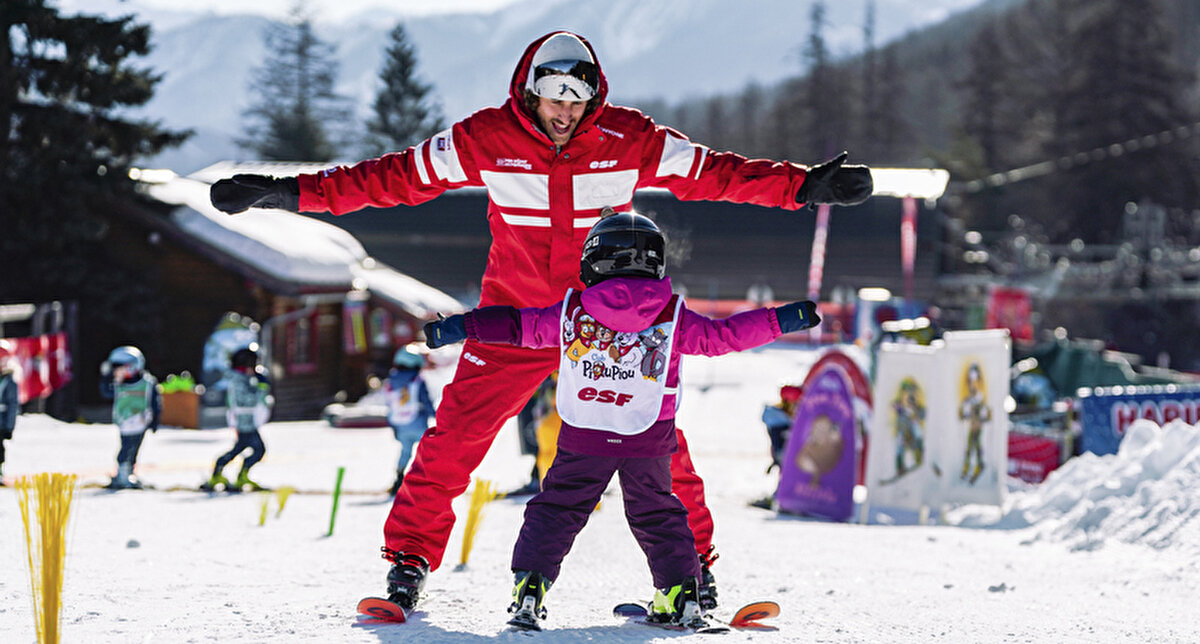 Moniteur esf apprenant à skier à un enfant au Club Piou Piou