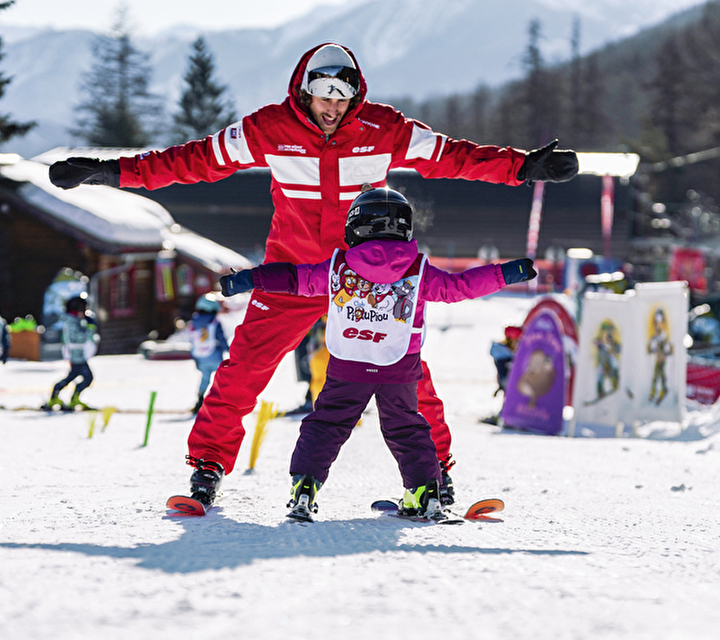 Moniteur esf apprenant à skier à un enfant au Club Piou Piou