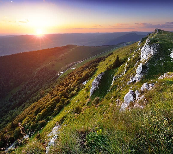 Vue pentue sur la montagne et sa verdure environnante face à un coucher de soleil