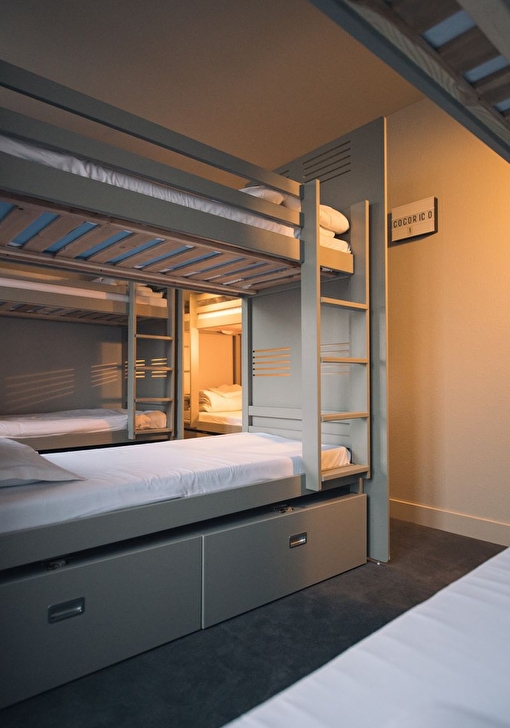 Intérieur d'une chambre proposant des lits superposés et caissons de rangement pour ranger ses affaires personnelles