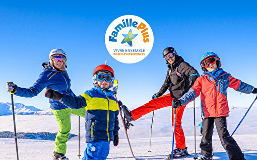 Famille avec deux parents et deux enfants sur une piste de ski avec logo du label Famille Plus