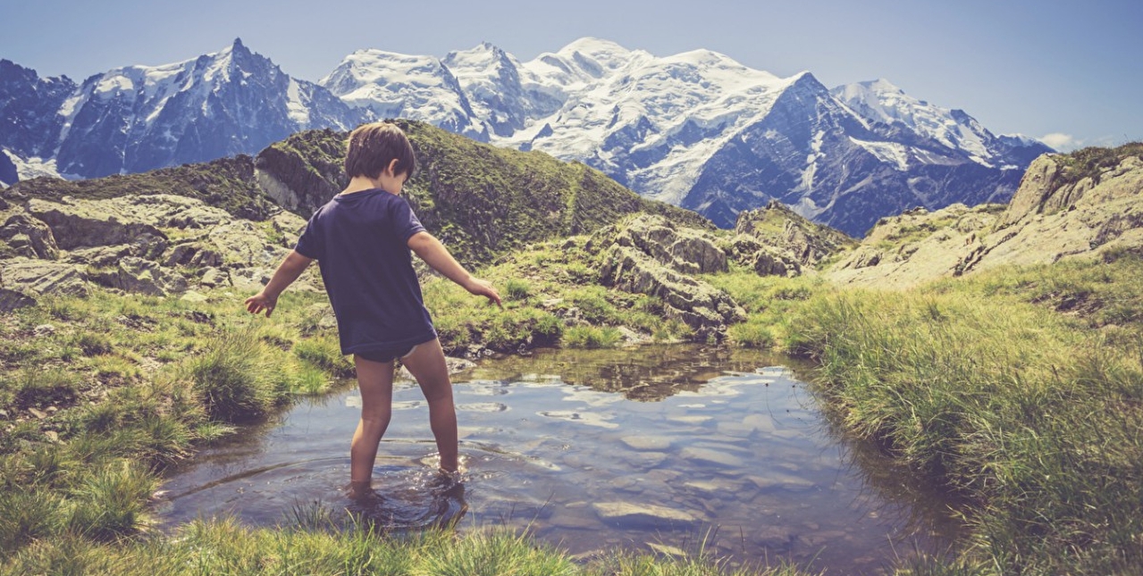 Enfant profitant des joies de la montagne en se trempant les pieds dans l'eau