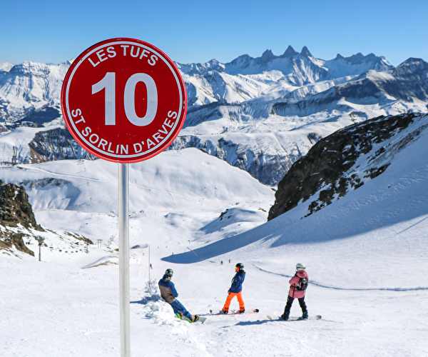 Panneau de piste rouge et skieurs en arrière plan