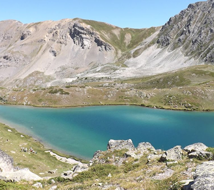 Lac aux nuances turquoises au milieu des montagnes sous un ciel bleu