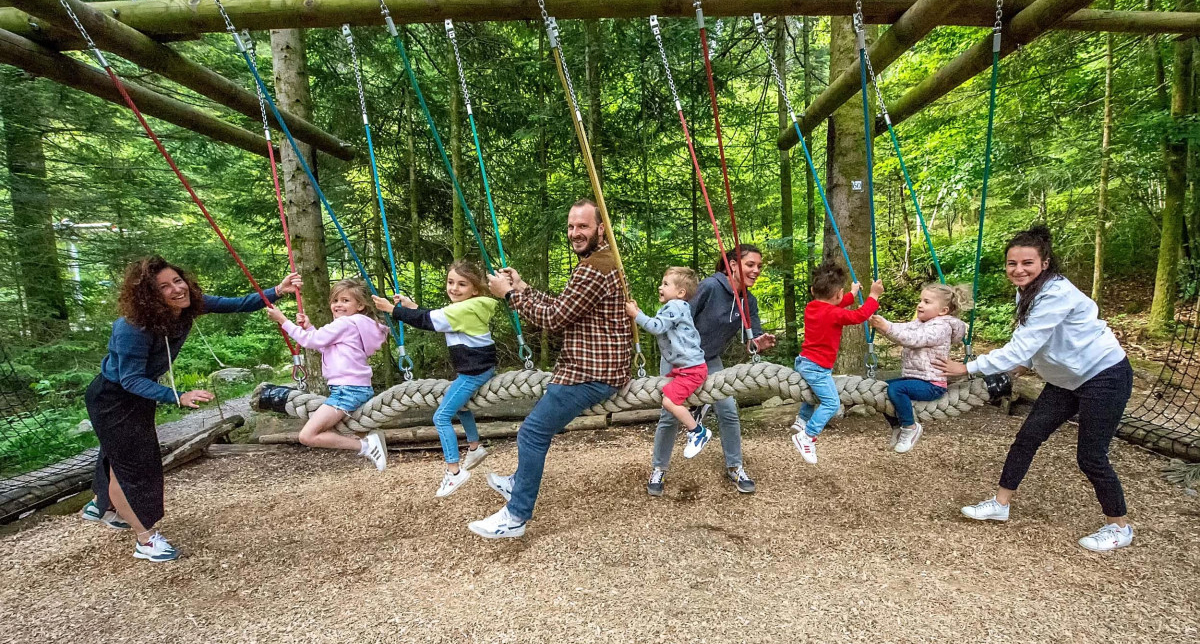 Parents et enfants sur une balançoire en bois dans une forêt
