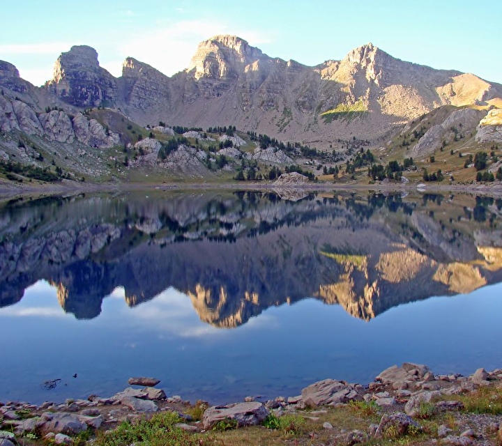 Montagnes rocheuses se reflétant dans un lac sous un ciel bleu