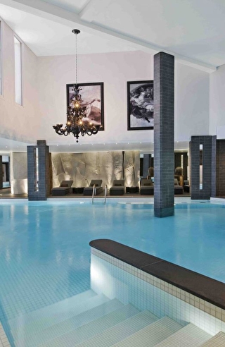 Vue sur la piscine intérieure d'un spa et son espace détente