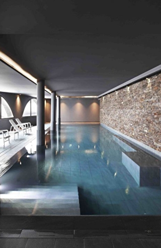 Vue sur la piscine intérieure d'un spa et son espace détente
