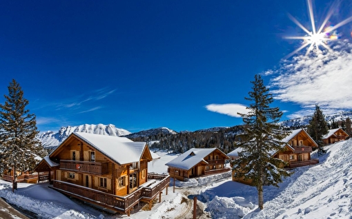 Chalets de montagne en bois recouverts de neige en montagne sous le ciel bleu