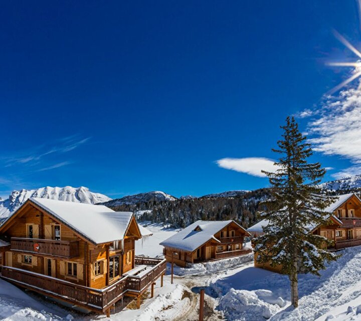 Chalets de montagne en bois recouverts de neige en montagne sous le ciel bleu