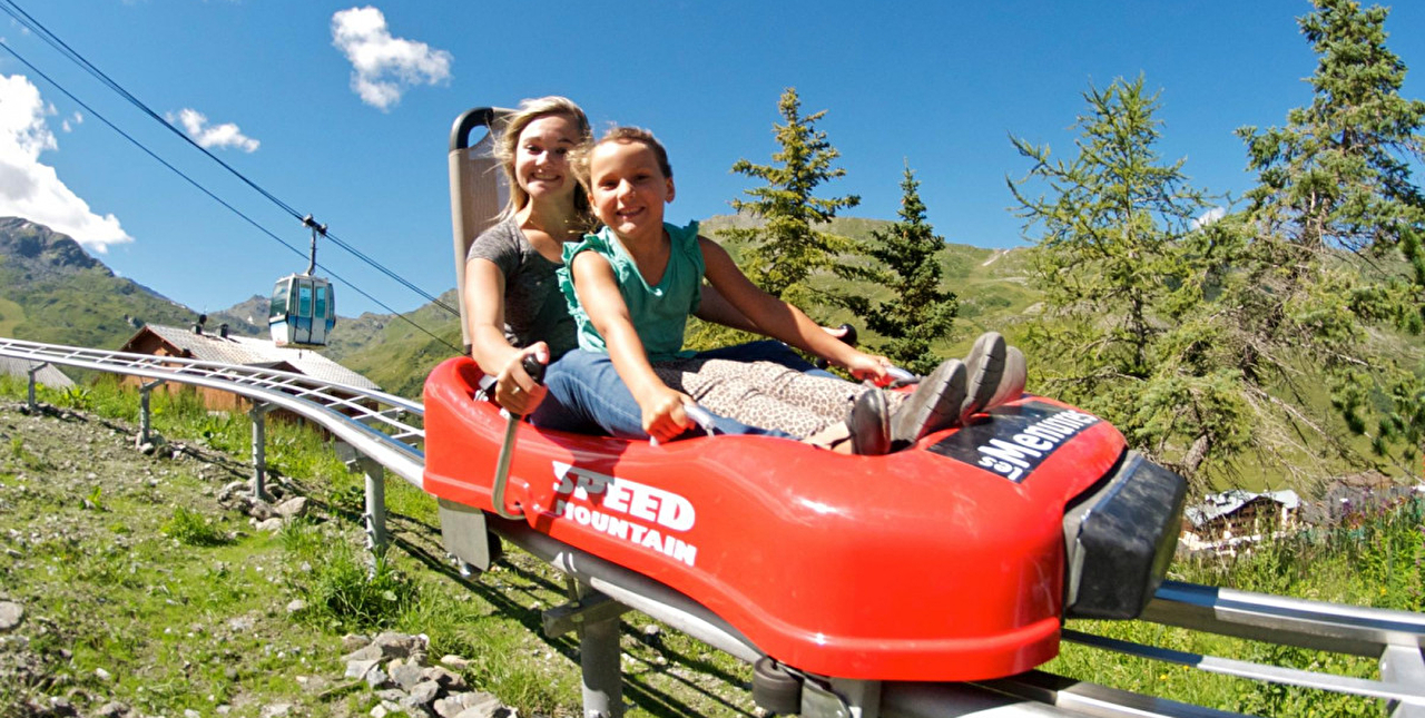 deux personnes effectuant une descente en luge d'été sur rail en montagne
