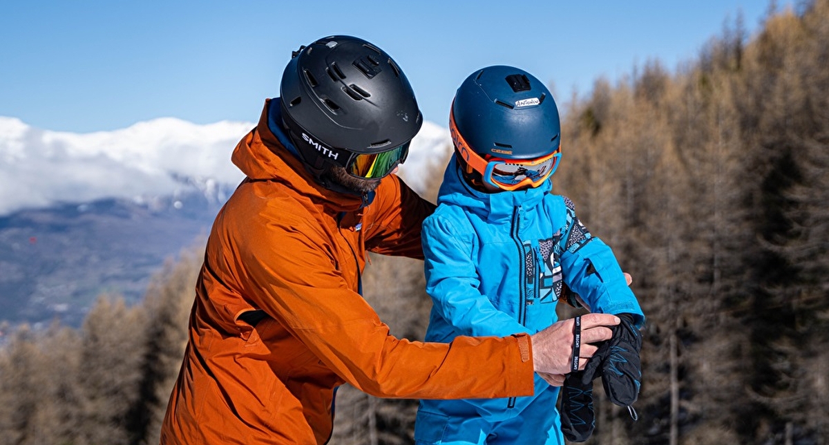 Parent et enfant en train de se préparer pour skier sur une piste