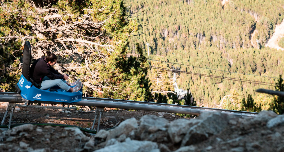 Femme en descente sur une luge sur rail en montagne