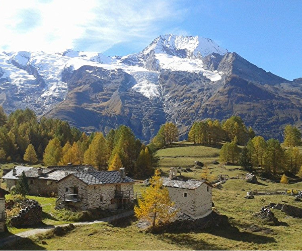 Vue sur le village entouré de verdure, de sapins et des montagnes en été