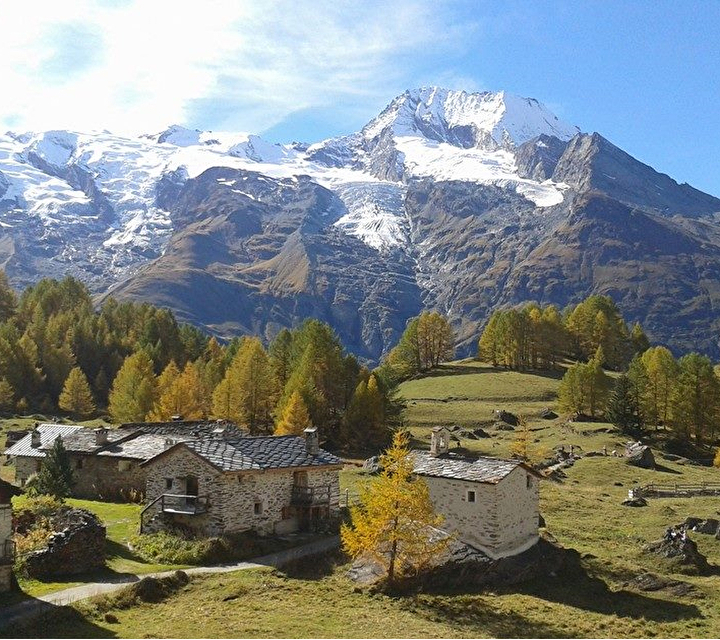 Vue sur le village entouré de verdure, de sapins et des montagnes en été
