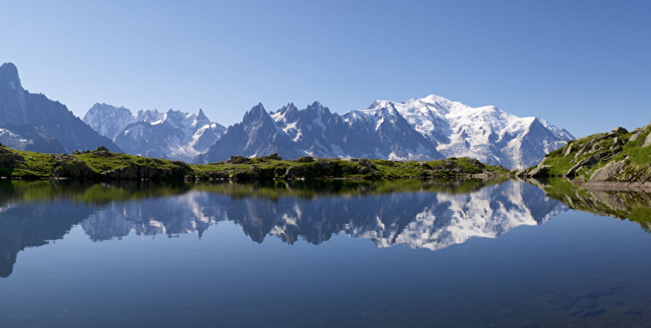 Vue plongeante sur un lac entouré de verdure et des montagnes enneigées