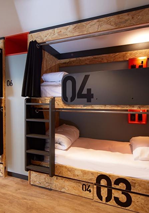 Chambre à coucher avec plusieurs lits superposés, leurs draps et échelles pour y monter