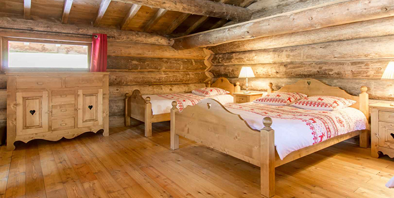 Intérieur d'une chambre à coucher dans un chalet bois avec un lit 2 places et des rangements pour les affaires personnelles