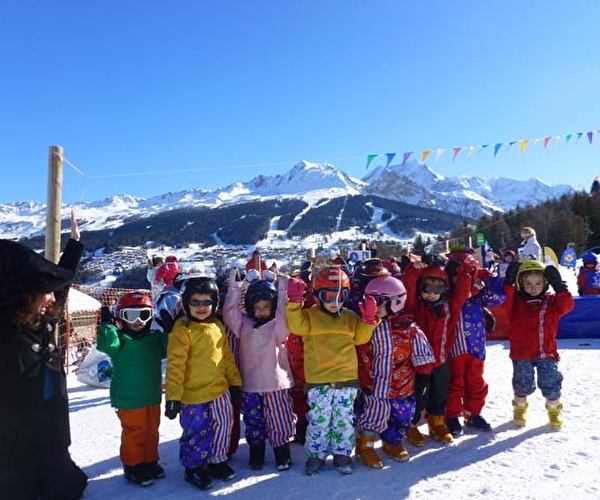 Groupe d'enfants dans la neige avec mascotte de la station