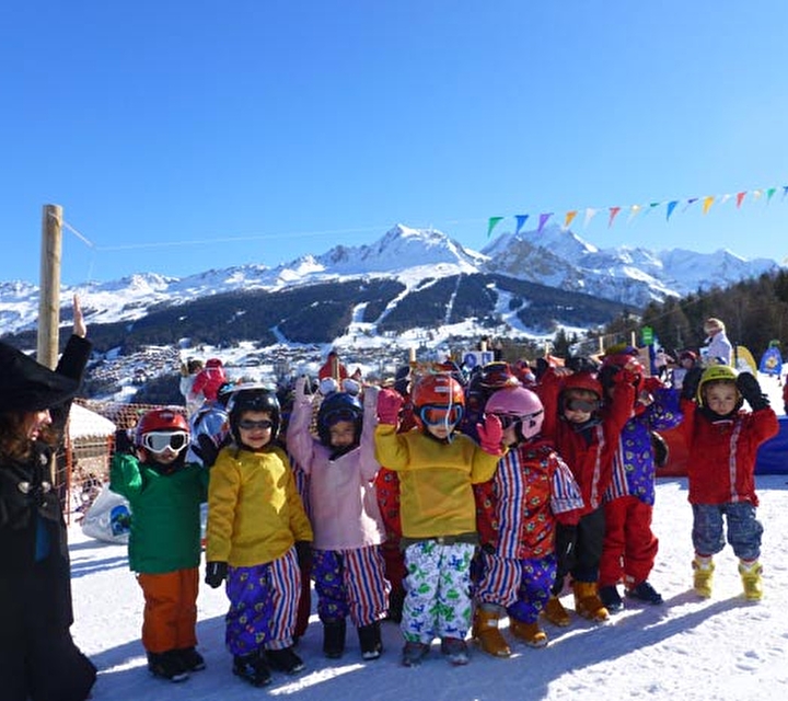 Groupe d'enfants dans la neige avec mascotte de la station