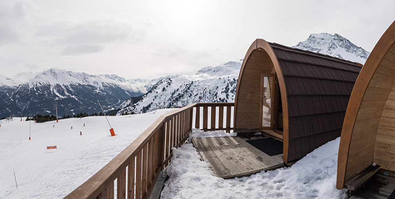 Cabane en bois aux airs d'igloo avec vue sur la montagne enneigée