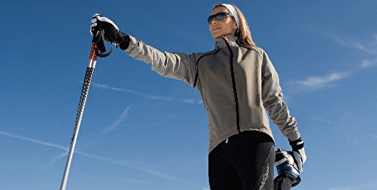 Femme sur une piste de montagne en hiver effectuant une séance d'étirements