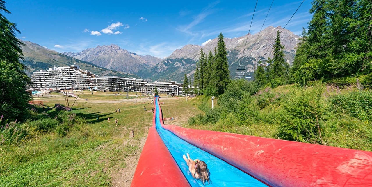 Enfant qui glisse sur un water slide sur une piste en été