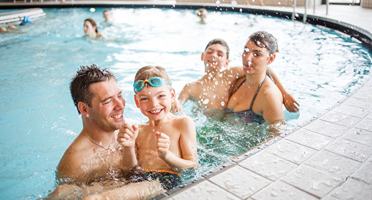 Famille avec deux parents et deux enfants qui s'amusent dans une piscine