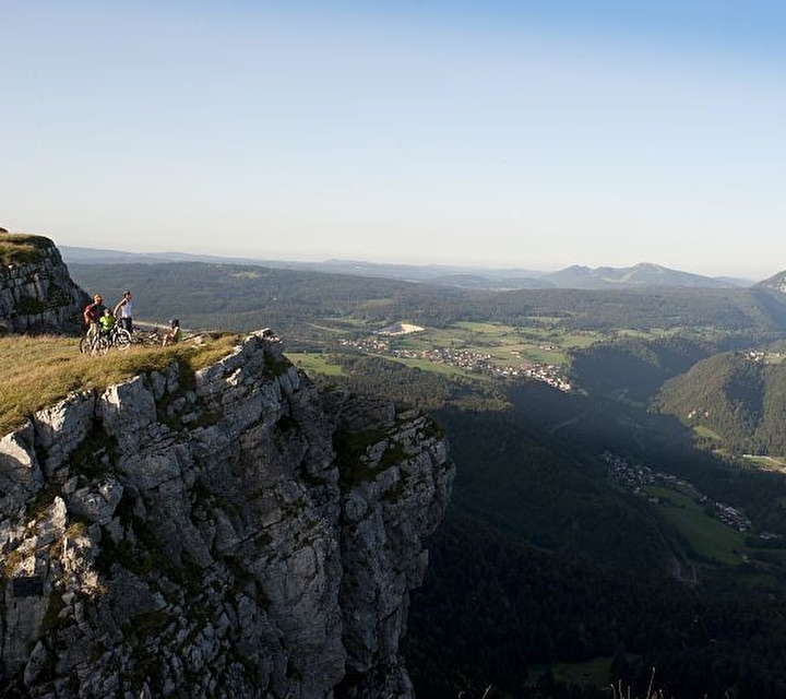 Groupe de personnes effectuant une balade à vélo au sommet d'une montagne verdoyante regardant le panorama