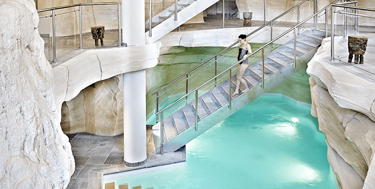 Femme descendant un escalier pour rejoindre la piscine intérieure d'un spa