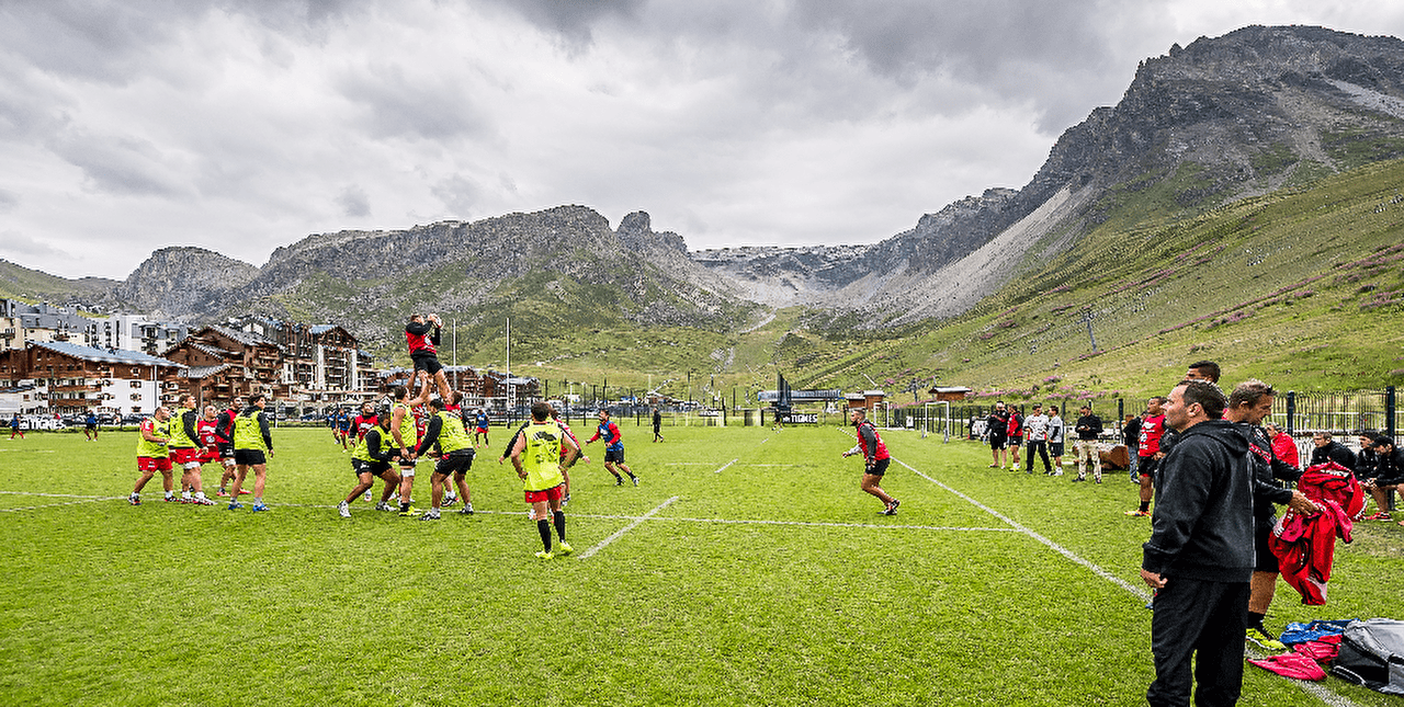 Équipes d'hommes effectuant un match sur un terrain de rugby proche des montagnes