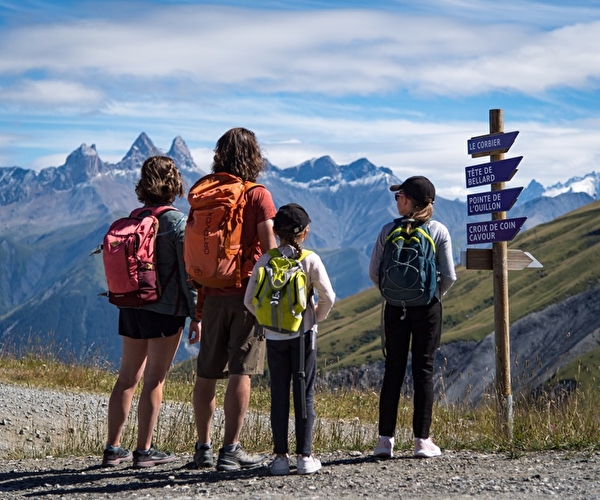 Maman avec ses 3 enfants équipés de sacs de randonnées, admirant la vue sur les montagnes