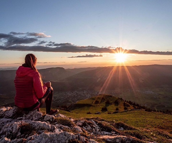 Femme assise sur la roche observant un coucher de soleil