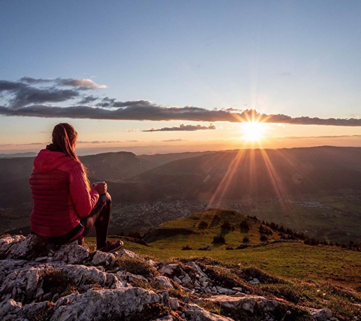 Femme assise sur la roche observant un coucher de soleil