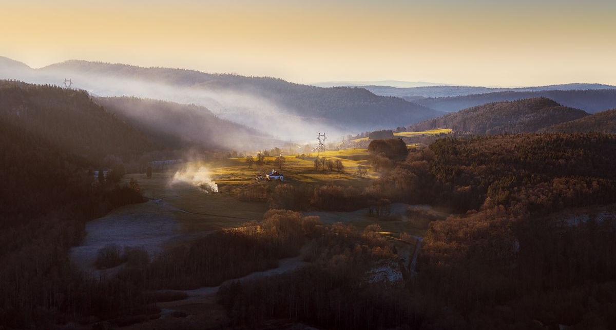 Vue panoramique sur les montagnes et vertes ornées de sapins et d'arbres sous une couche de nuages brumeux