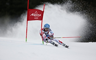 Personne effectuant une descente de slalom et franchissant une porte sur une piste de ski en montagne l'hiver