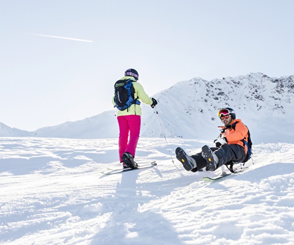 Personne à ski et une autre sur un snooc en haut d'une montagne prêt à descendre la pente enneigée