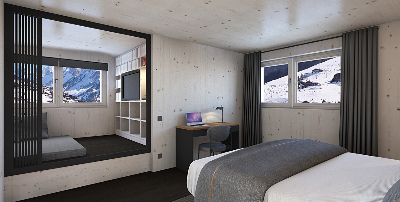 Intérieur d'une chambre à coucher avec lit double, coin bureau et un espace cocon avec tévision et vue sur les montagnes enneigées